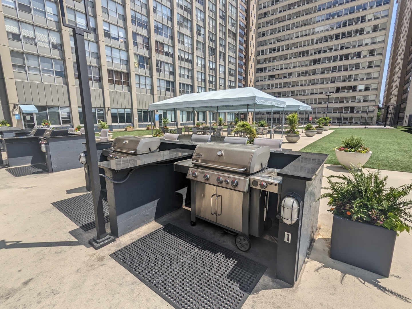 655 West Irving Park Road, Unit 617 Chicago, IL 60613 - Photo 32 of 33 a view of a patio with table and chairs under an umbrella with a barbeque