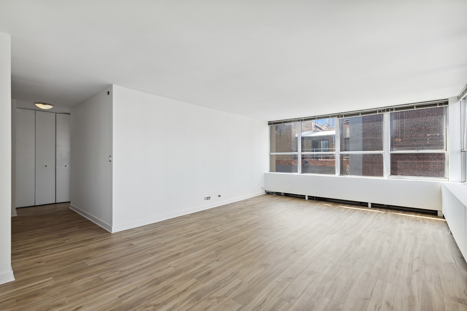 655 West Irving Park Road, Unit 617 Chicago, IL 60613 - Photo 6 of 33 a view of an empty room with wooden floor and a window