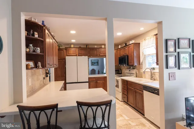 a kitchen with stainless steel appliances kitchen island granite countertop a table chairs and a refrigerator