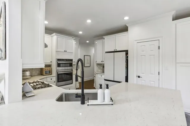 a white kitchen with white cabinets and stainless steel appliances