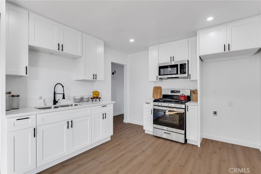 2124 East Oris Street Compton, CA 90222 - Photo 5 of 20 a kitchen with cabinets stainless steel appliances a sink and wooden floor