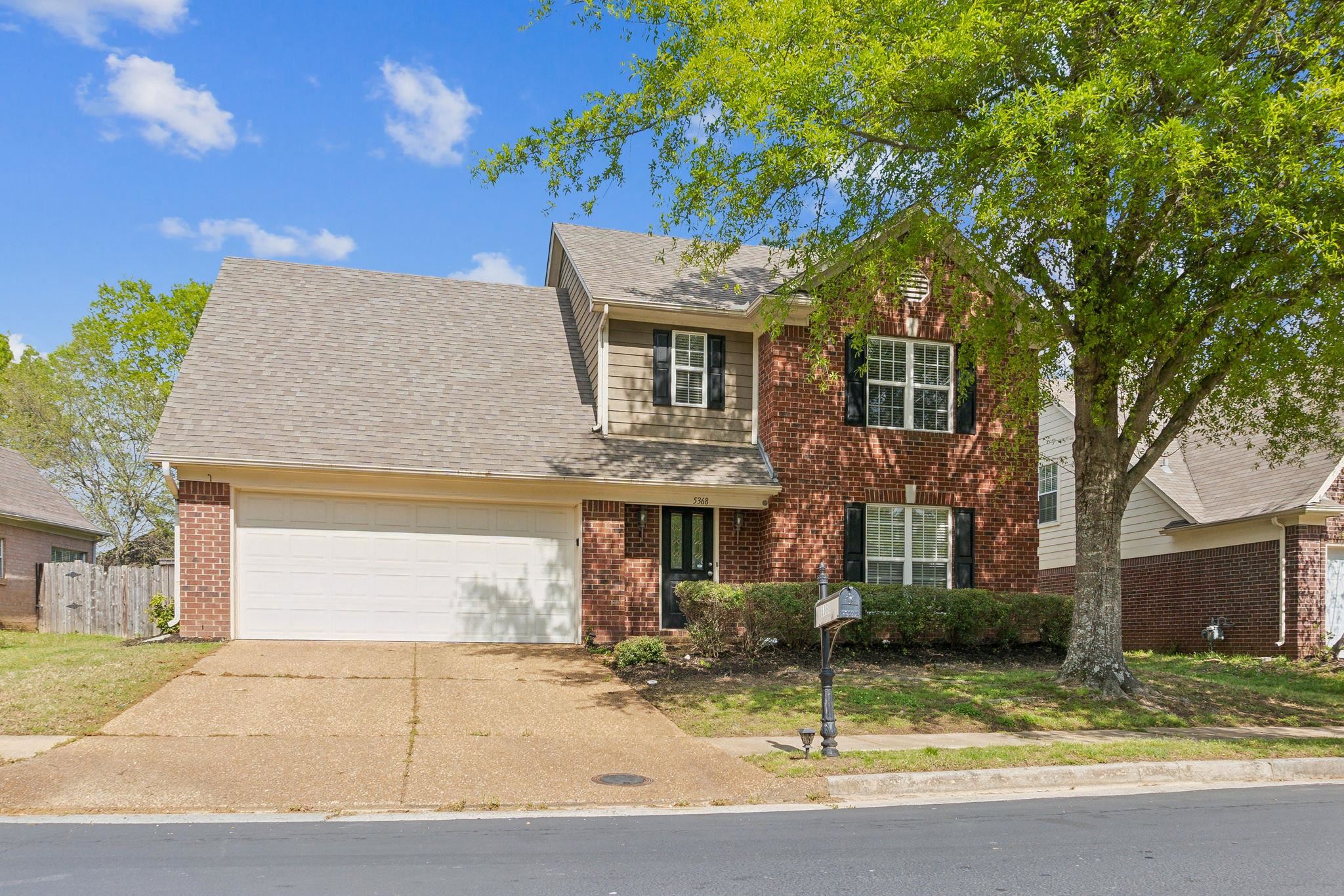 View of front of property with a garage, fence, concrete driveway, and brick siding
