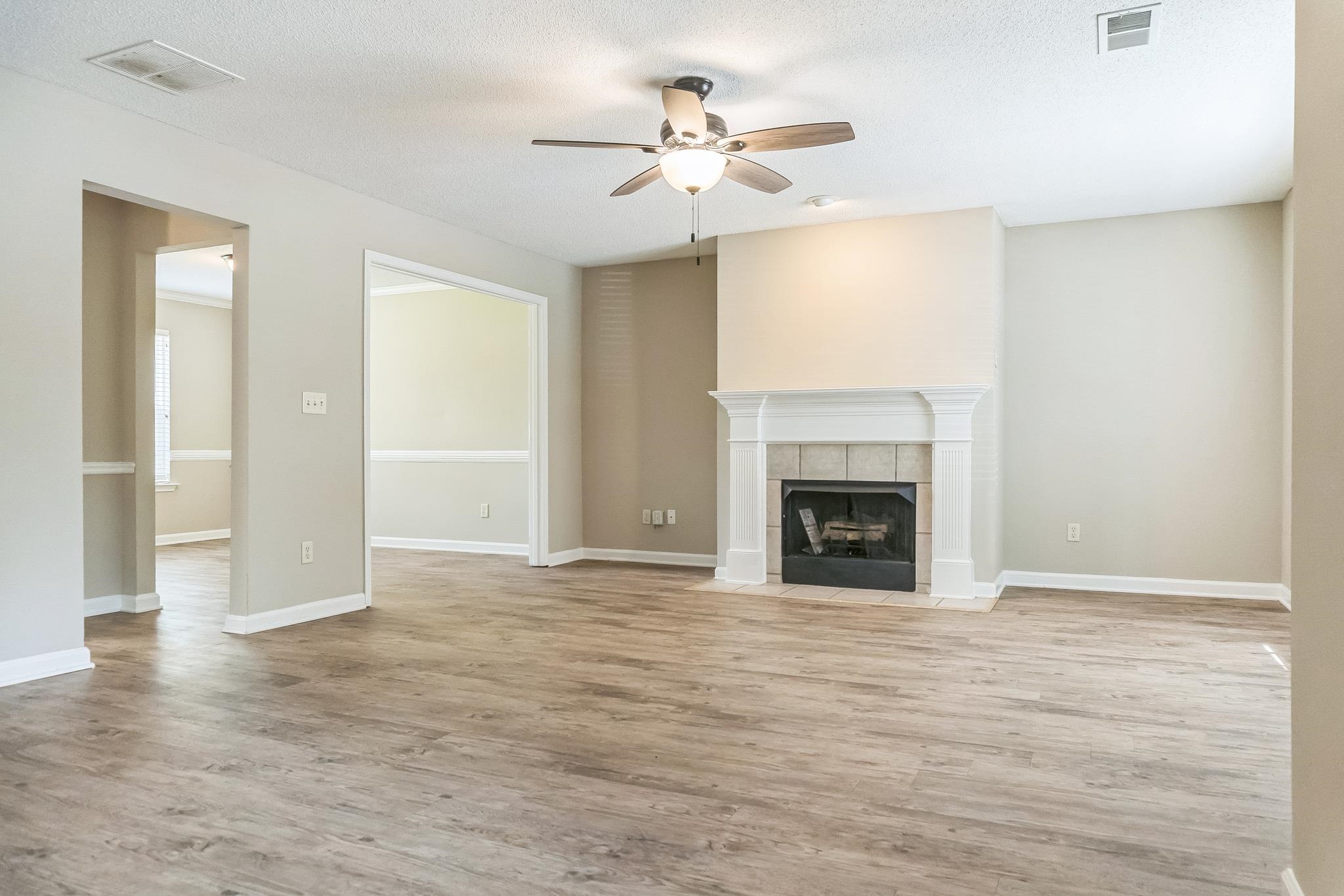 5368 Milton Ridge Drive Arlington, TN 38002 - Photo 3 of 15 Unfurnished living room with light wood-style flooring, visible vents, ceiling fan, and a tiled fireplace