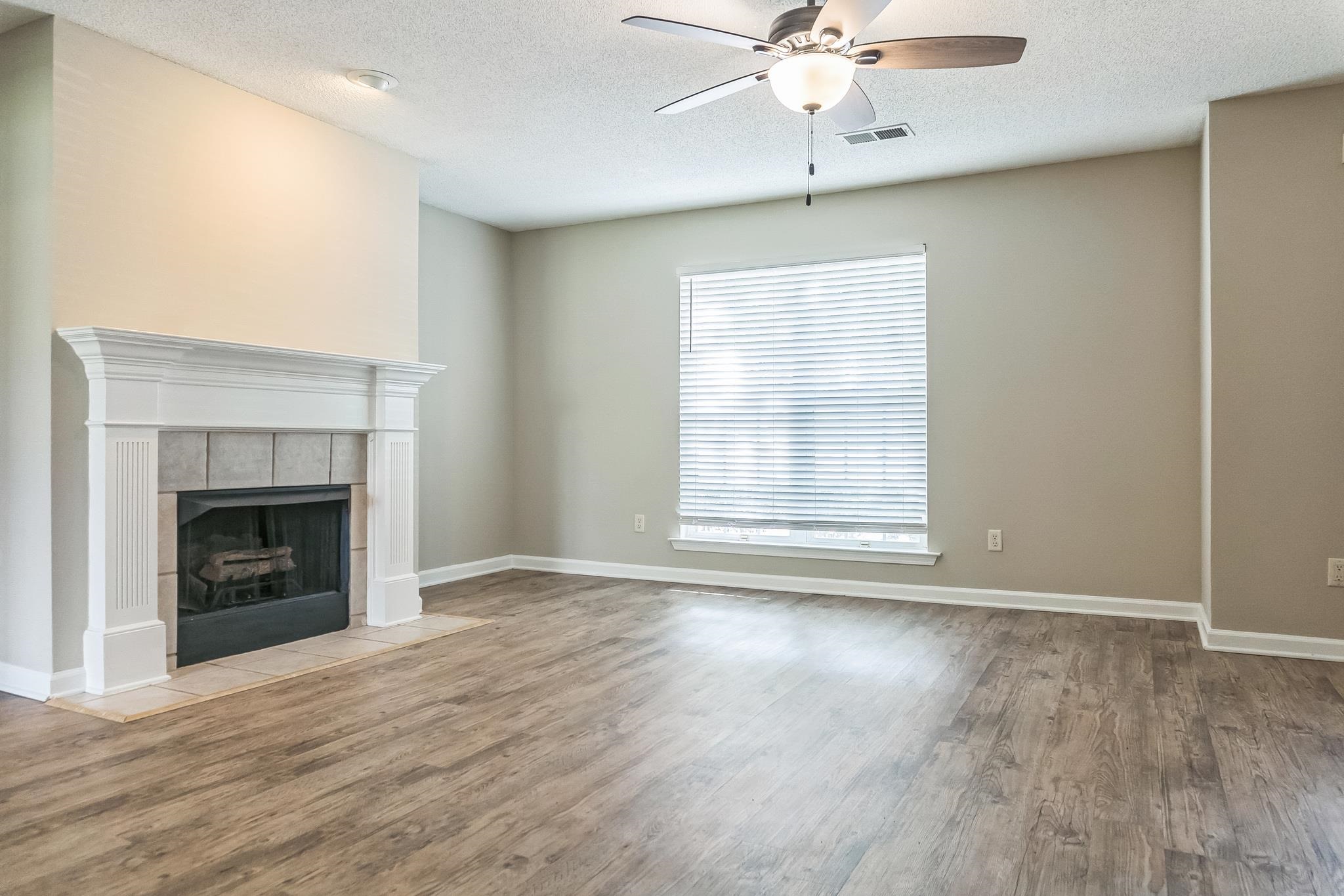 5368 Milton Ridge Drive Arlington, TN 38002 - Photo 4 of 15 Unfurnished living room with a fireplace, a textured ceiling, a ceiling fan, visible vents, and wood finished floors