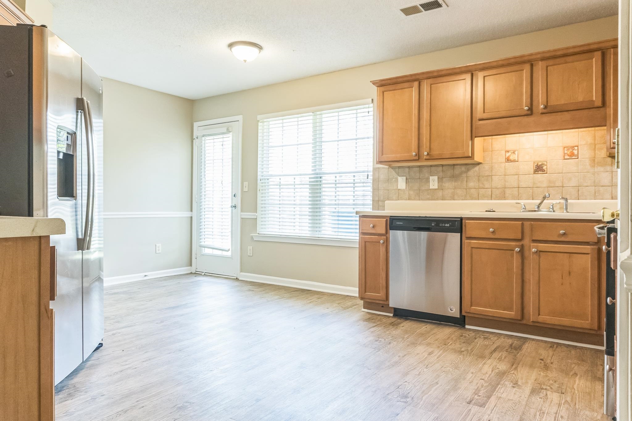 5368 Milton Ridge Drive Arlington, TN 38002 - Photo 5 of 15 Kitchen with light countertops, appliances with stainless steel finishes, brown cabinets, light wood finished floors, and decorative backsplash