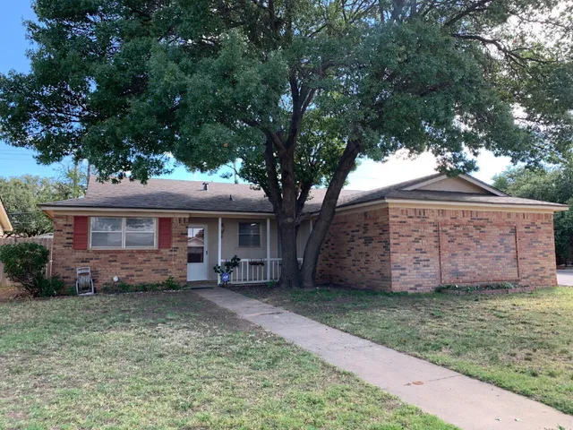 a view of a house with a yard and large tree