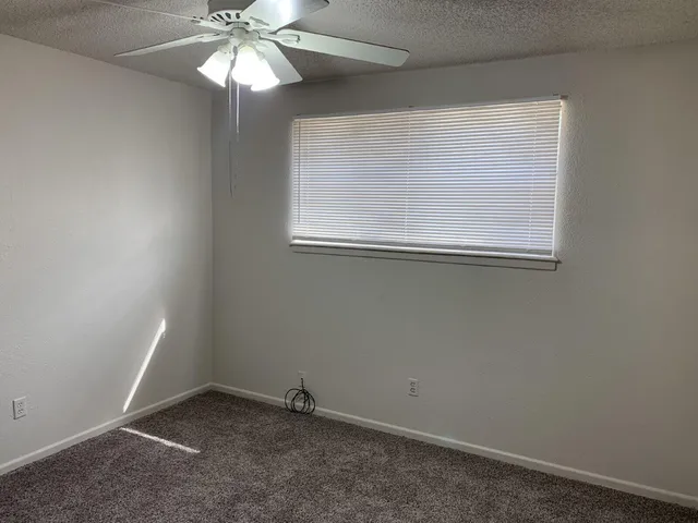 an empty room with a window and a fan