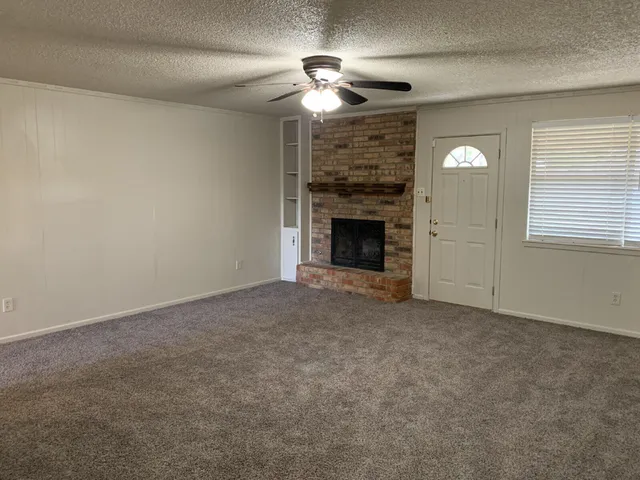 an empty room with a fireplace and chandelier fan