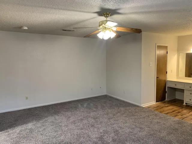 an empty room with a chandelier fan and a bathroom