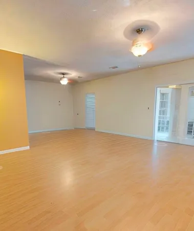a view of an empty room with window and wooden floor