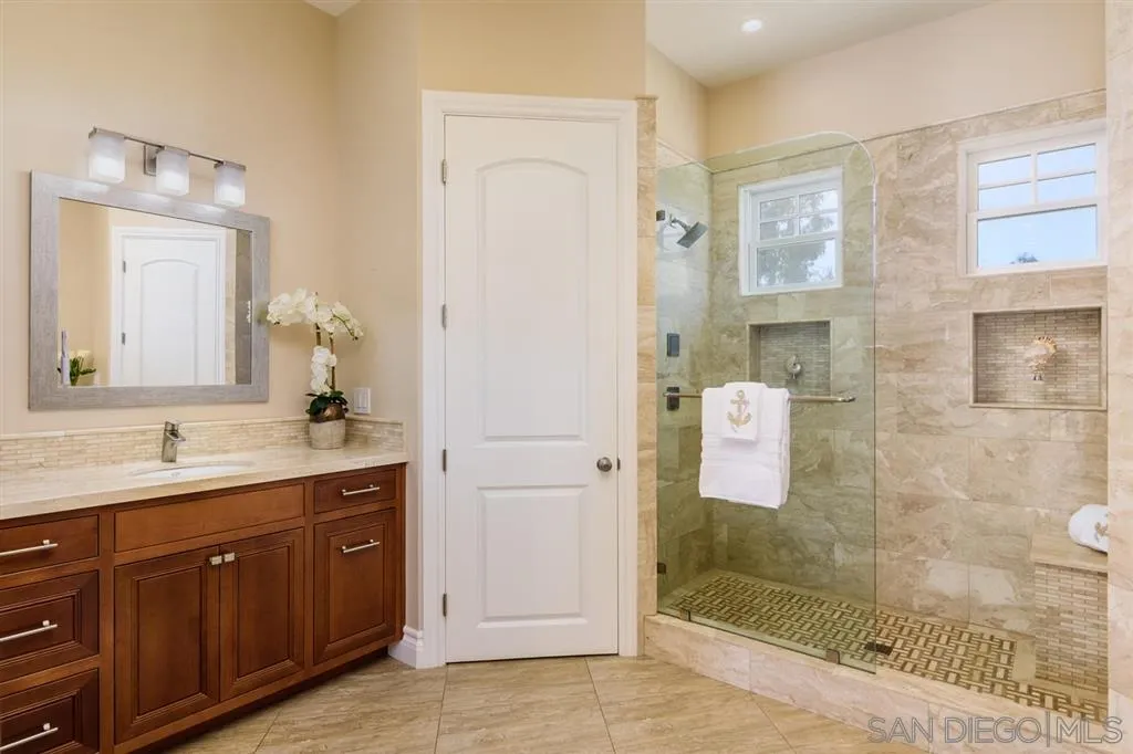 261 E Avenue Coronado, CA 92118 - Photo 13 of 25 a bathroom with a granite countertop sink mirror and shower