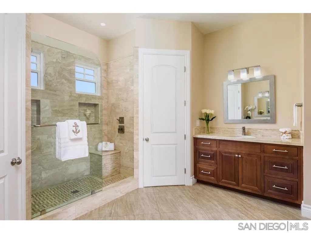 261 E Avenue Coronado, CA 92118 - Photo 14 of 25 a bathroom with a granite countertop sink a mirror and a shower