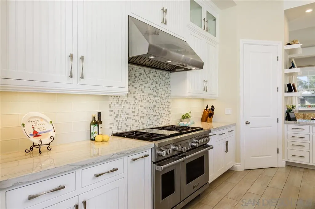 261 E Avenue Coronado, CA 92118 - Photo 7 of 25 a kitchen with granite countertop a stove and a white cabinets