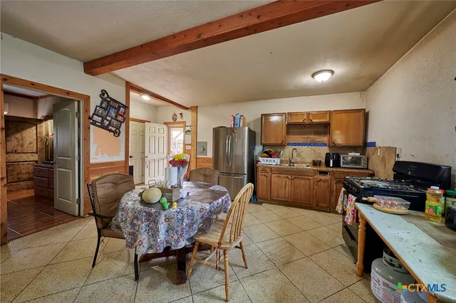 a kitchen with stainless steel appliances granite countertop a refrigerator a stove a sink a dining table and chairs with wooden floor