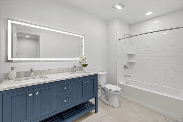 a bathroom with a double vanity sink toilet mirror and shower