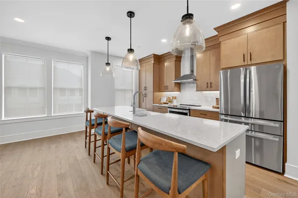 a kitchen with stainless steel appliances a refrigerator a sink dishwasher a stove and a dining table with wooden floor