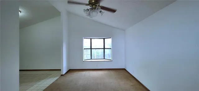 an empty room with windows and chandelier fan