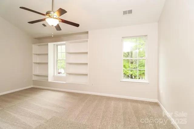 an empty room with a window and a ceiling fan