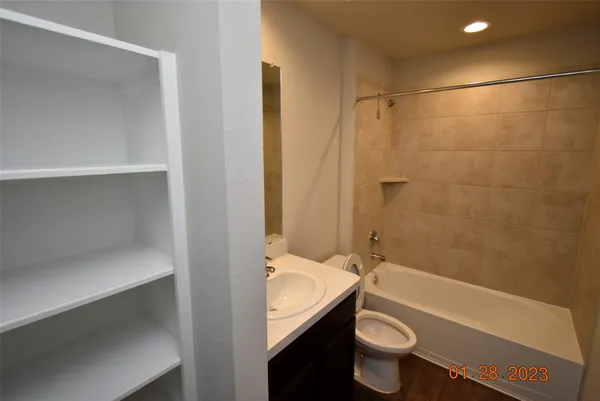 a bathroom with a granite countertop bathtub shower sink vanity and toilet