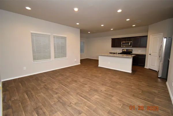 a view of kitchen with stainless steel appliances wooden floor and large window