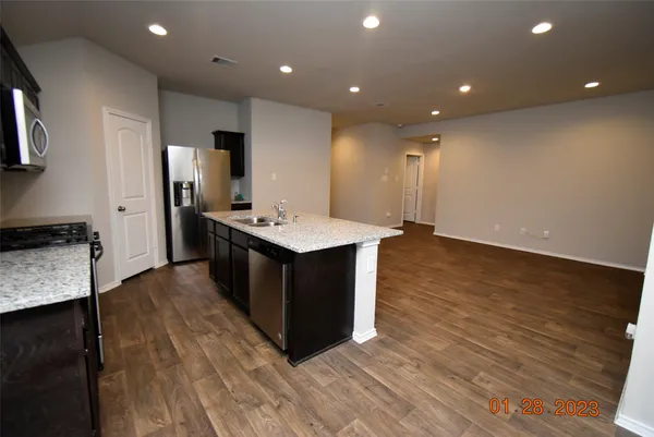 a large kitchen with stainless steel appliances a large counter top a sink and a stove