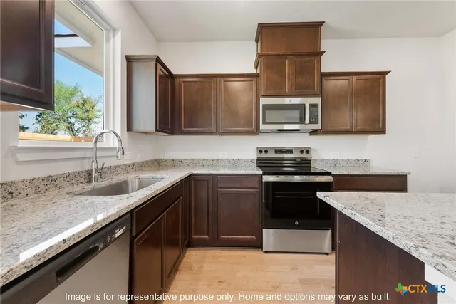 a kitchen with granite countertop a sink and stove top oven
