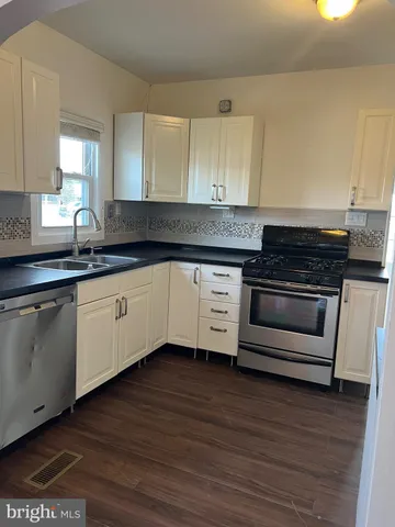 a kitchen with granite countertop a sink cabinets and wooden floor