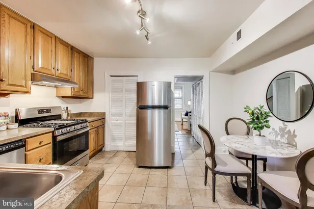 a kitchen with stainless steel appliances granite countertop a dining table chairs refrigerator and cabinets