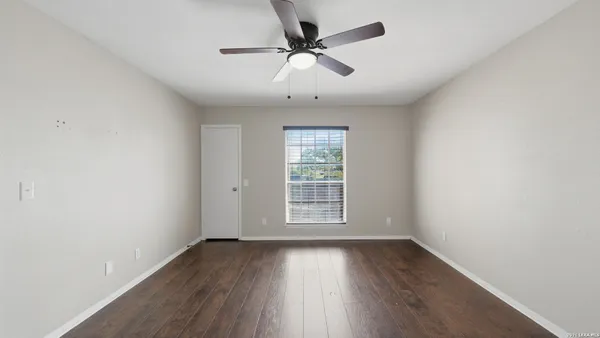 a view of empty room with wooden floor and ceiling fan