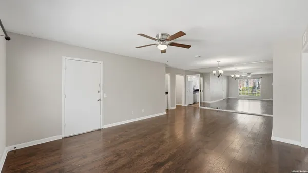 an empty room with wooden floor and kitchen view