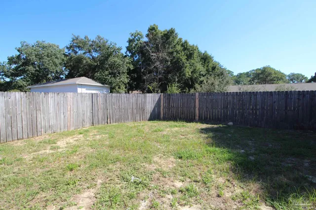 a view of a backyard with large trees and wooden fence