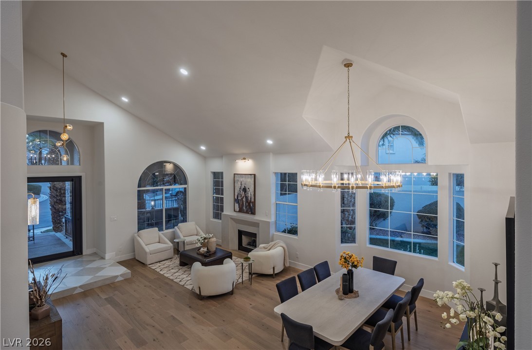 8800 Lusso Las Vegas, NV 89134 - Photo 60 of 85 Dining space featuring a glass covered fireplace, lofted ceiling, a chandelier, wood finished floors, and plenty of natural light