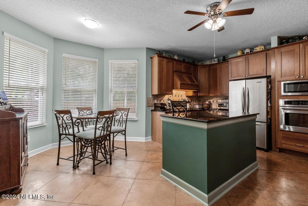 8225 Hardwood Landing Road St. Augustine, FL 32092 - Photo 10 of 126 a kitchen with stainless steel appliances kitchen island granite countertop a refrigerator a stove a sink a dining table and chairs