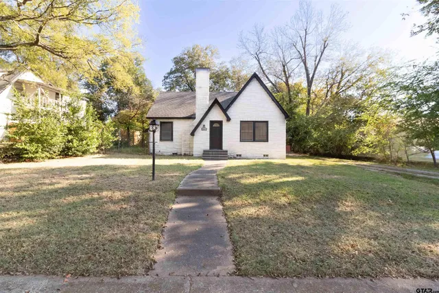 a view of a yard in front of a house with large trees