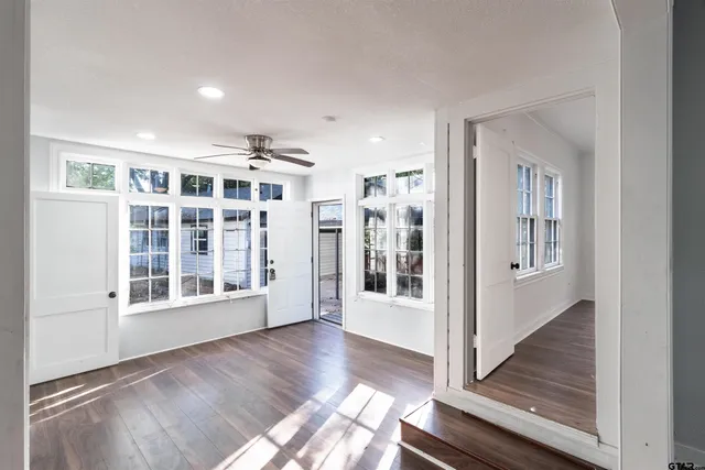 a view of an empty room with wooden floor and a window