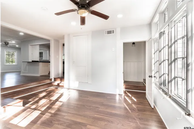 a view of a hallway to a room with wooden floor and a window