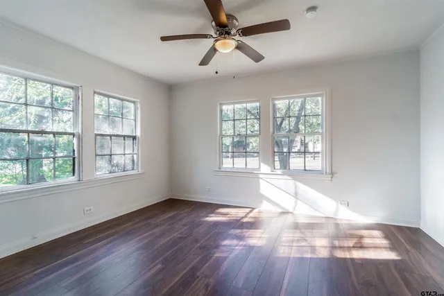 a view of an empty room with wooden floor and a window