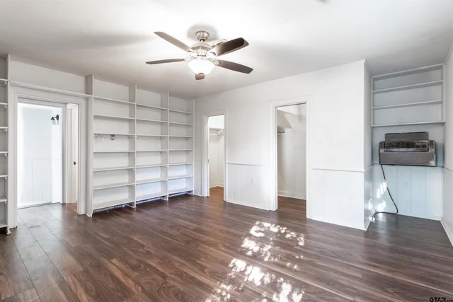 an empty room with wooden floor closet and windows