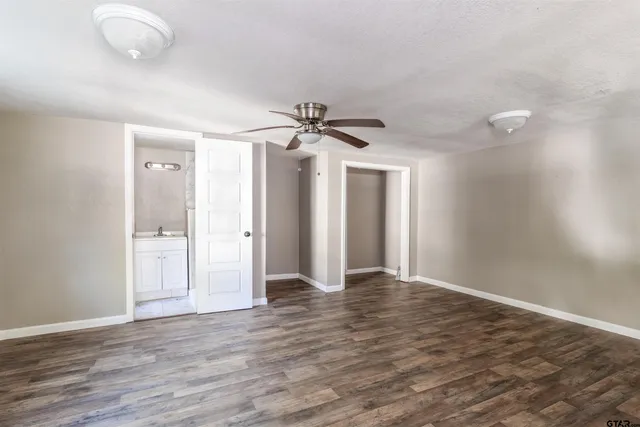 an empty room with wooden floor and a ceiling fan
