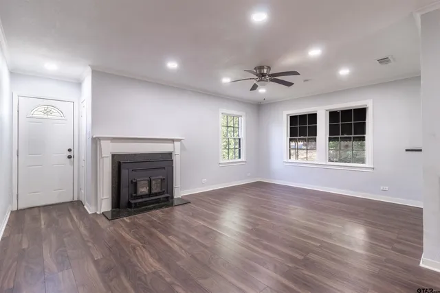 an empty room with windows a fireplace and a wooden floor