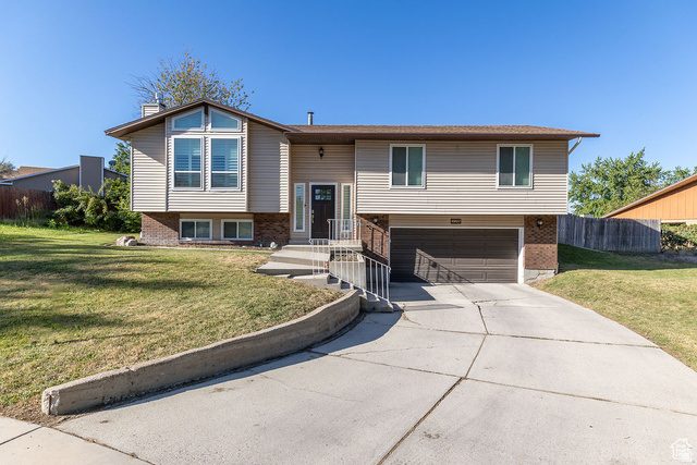 228 Golden Willow Circle Sandy, UT 84070 - Photo 1 of 1 Bi-level home featuring a chimney, brick siding, a garage, and driveway