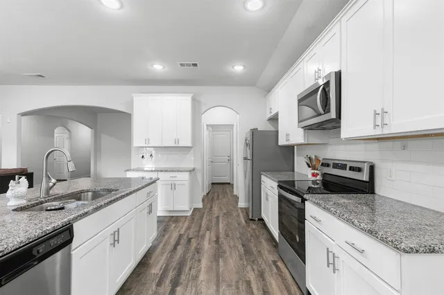 a large kitchen with stainless steel appliances granite countertop a lot of counter space and wooden floor
