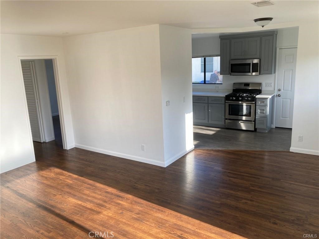 8312 Barnsley Avenue Los Angeles, CA 90045 - Photo 3 of 17 an empty room with wooden floor and a kitchen