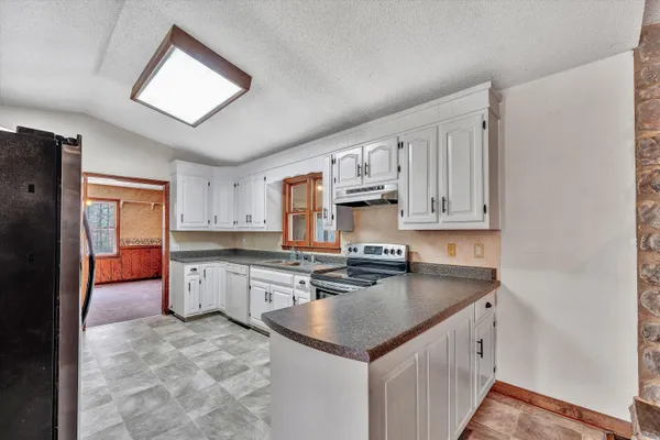 a kitchen with granite countertop white cabinets white stainless steel appliances with a sink and dishwasher