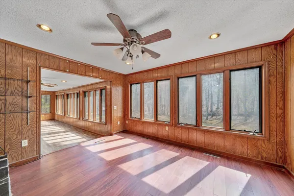 an empty room with chandelier fan and windows