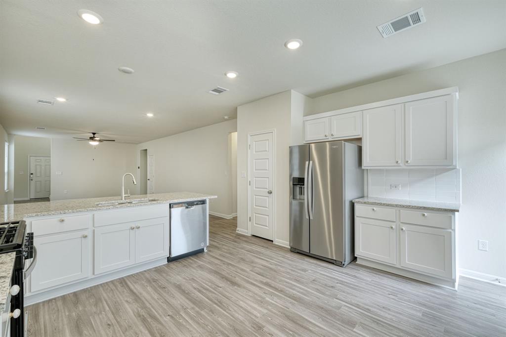 8307 Haflinger Drive Austin, TX 78747 - Photo 2 of 13 Kitchen featuring appliances with stainless steel finishes, white cabinetry, light stone countertops, light wood finished floors, and recessed lighting