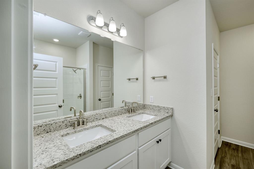 8307 Haflinger Drive Austin, TX 78747 - Photo 4 of 13 Full bath featuring a shower stall, double vanity, and dark wood-style flooring