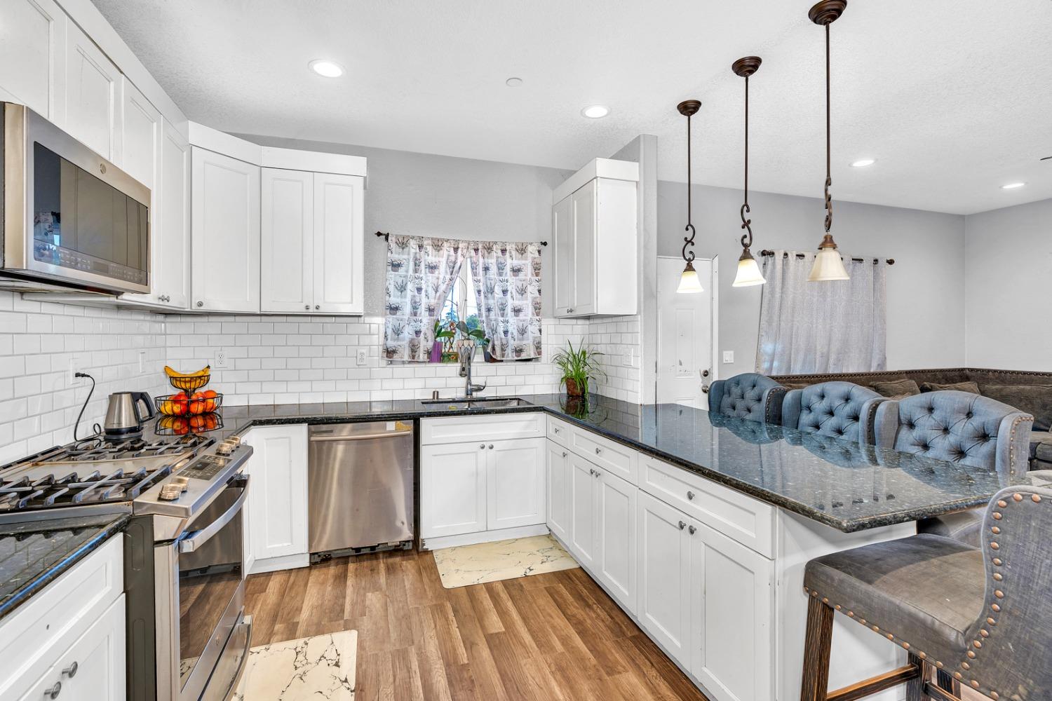 509 Kerr Avenue Modesto, CA 95354 - Photo 21 of 55 a kitchen with stainless steel appliances granite countertop a stove a sink and white cabinets
