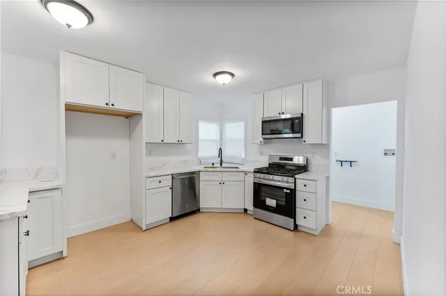 a kitchen with granite countertop white cabinets and stainless steel appliances