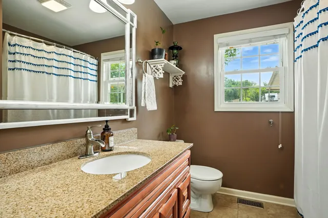 a bathroom with a granite countertop sink toilet and a mirror